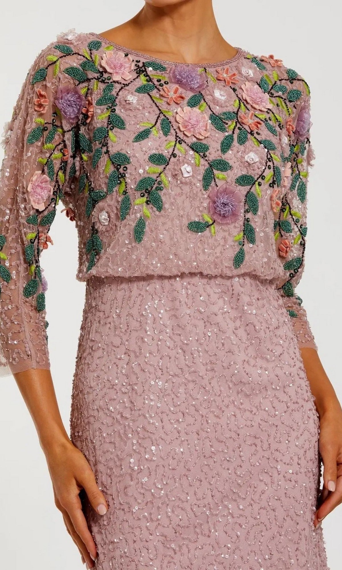 A woman wearing the Mac Duggal 9341 long formal dress in purple, featuring three-quarter sleeves, floral embroidery and sequins adorning the bodice, with sheer detailing on the upper sections.